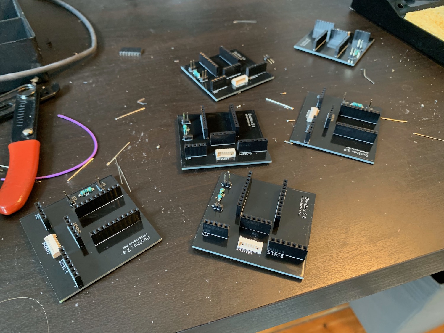 Six full-soldered Dustboxes on a desk with off-cuts or wire and tools in view