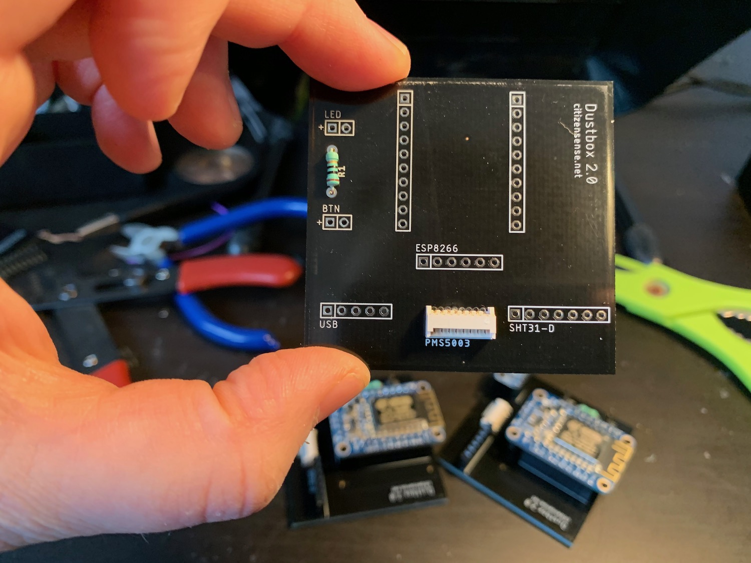 A Dustbox 2.0 is held up to show the resistor and PicoBlade connector soldered on